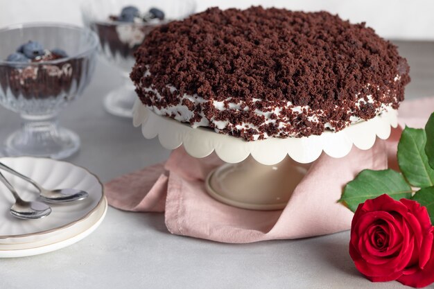 Hausgemachte Schokoladenpastete auf Ständer und rote Rosenblume