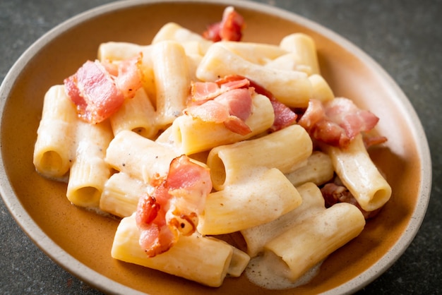 hausgemachte Spaghetti-Rigatoni-Nudeln mit weißer Soße und Speck - italienische Küche