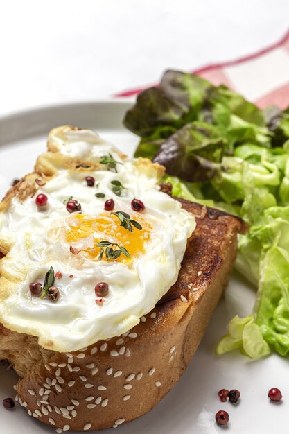 Hausgemachte Spiegeleier mit Brioche-Salat auf weißem Teller