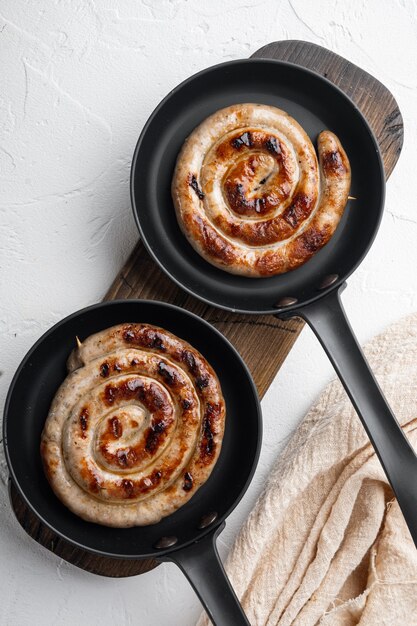 Hausgemachte Spiral gegrillte Wurst in Gusseisen Pfanne, auf weißem Hintergrund, Draufsicht flach legen