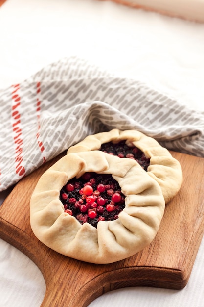 Hausgemachte süße Galette mit Holunderbeeren und Preiselbeeren auf einem Holzbrett