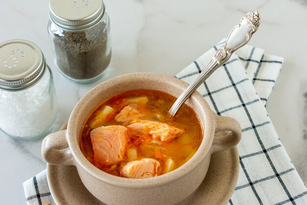 Hausgemachte Suppe mit Lachs mit Brotstangen auf Marmorhintergrund.