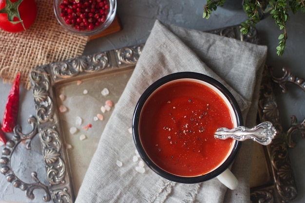 Hausgemachte Tomatensuppe in einem Becher mit frischen Kräutern, Knoblauch, Paprika und Himalaya-Salz