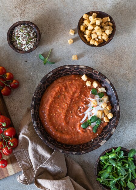 Hausgemachte Tomatensuppe mit Sahnecroutons und Microgreen in Holzschale