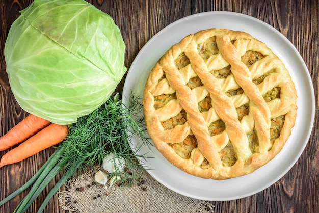 Hausgemachte Torte mit Kohl, Karotten, Zwiebeln und Fleisch auf Holz