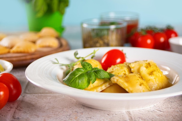 Hausgemachte traditionelle italienische Ravioli-Nudeln mit Basilikum und Tomatenkirschgemüse auf dem Tisch