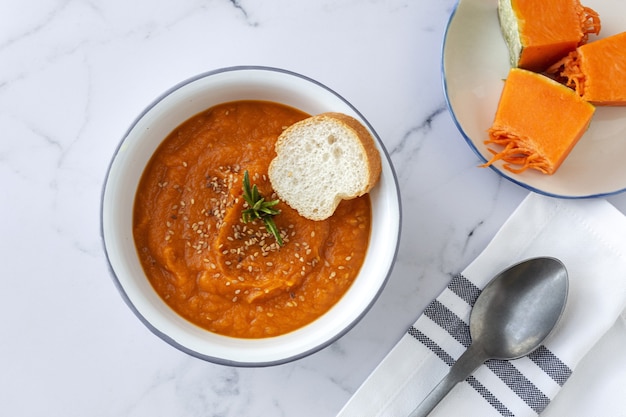 Hausgemachte und gesunde Kürbiscreme mit Brot von oben auf Marmortisch. Flach liegen