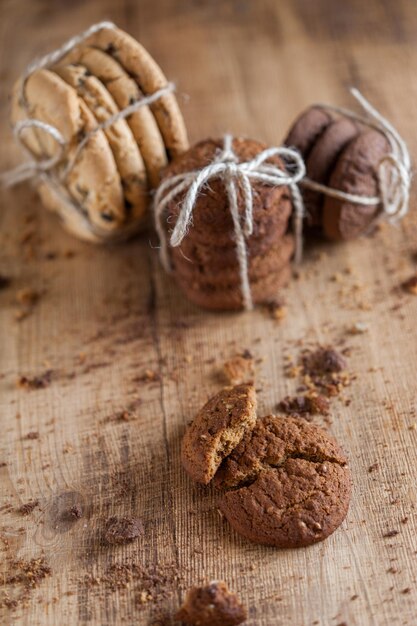 Hausgemachte vollkornkekse mit haferflocken, leinen und sesam und traditionelle amerikanische kekse mit schokoladenstückchen auf dunklem rustikalem holztisch. gesundes veganes ernährungskonzept.