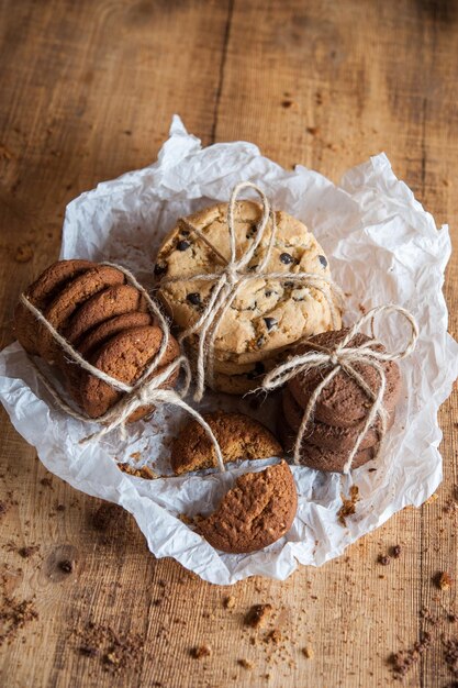 Hausgemachte Vollkornkekse mit Haferflocken, Leinen und Sesam und traditionelle amerikanische Kekse mit Schokoladenstückchen auf dunklem rustikalem Holztisch. Gesundes veganes Ernährungskonzept.