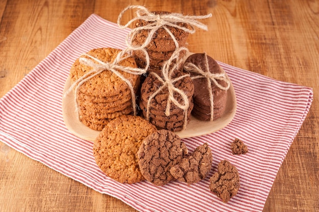 Hausgemachte Vollkornkekse mit Haferflocken, Leinen und Sesam und traditionelle Kekse mit Schokoladenstückchen auf dunklem rustikalem Holztisch.