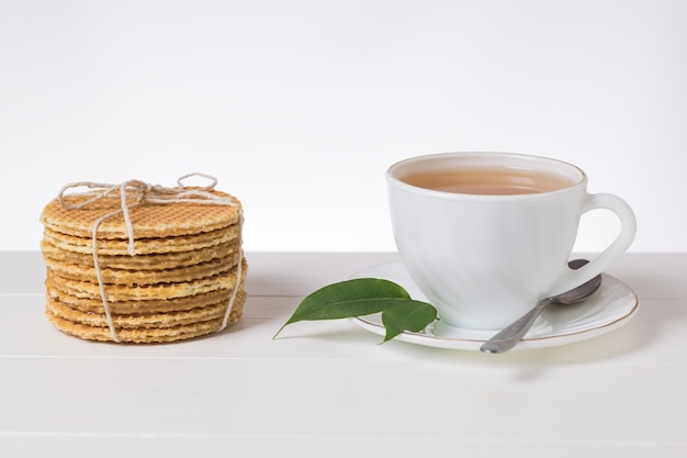 Hausgemachte Waffeln und frischer Tee auf einem weißen Tisch auf hellem Hintergrund. Hausgemachte Kuchen mit Tee.