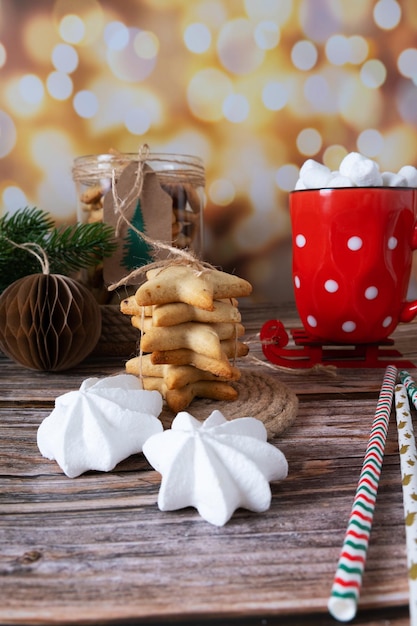 Hausgemachte Weihnachtsplätzchen übereinander gestapelt mit einer Tasse heißem Kakao mit Marshmallow