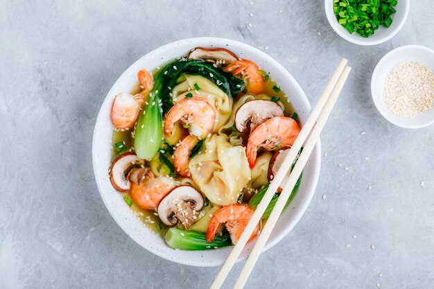 Hausgemachte Wonton-Suppe mit Knödeln, braunen Pilzen, Bok Choy und Garnelen Draufsicht kopieren