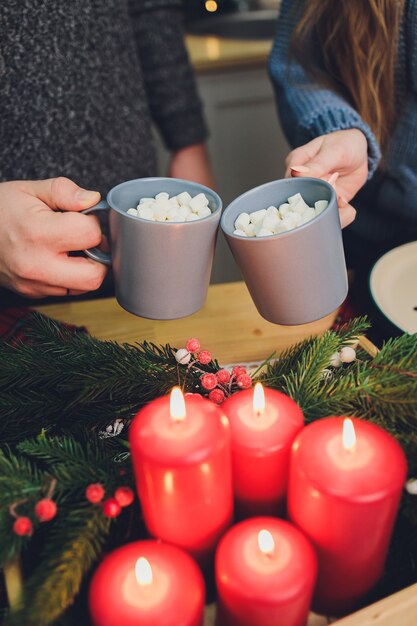 Hausgemachte zwei Kakaogläser mit Marshmallows. Heißes Wintergetränk auf hölzernem Hintergrund, verziert mit Zimtstangen und Tannenzweigen.