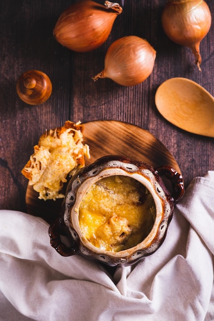 Hausgemachte Zwiebelsuppe mit Käse-Croutons in einem Topf auf der Tischplatte und vertikaler Ansicht