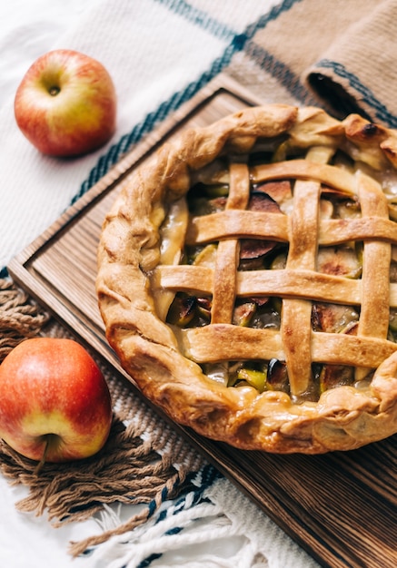 Hausgemachter Apfelkuchen auf einem Holzbrett mit Zimt und einer goldenen Kruste. Herbstsaison