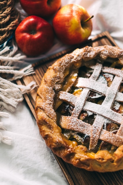 Hausgemachter Apfelkuchen auf einem Holzbrett mit Zimt und einer goldenen Kruste. Herbstsaison