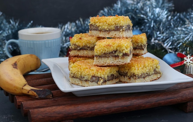 Hausgemachter Bananenkuchen mit Kokosflocken festliches Dessert für Weihnachten Neujahr Closeup mit Tasse Kaffee im Hintergrund