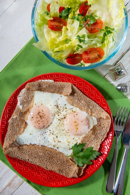 Hausgemachter bretonischer Crêpe mit Ei im roten Teller