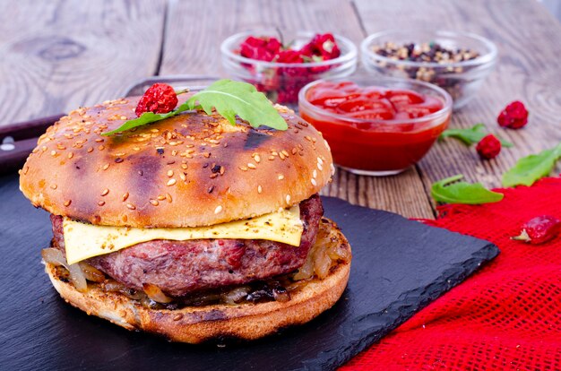 Hausgemachter Burger mit Sesambrötchen und Rinderhackfleisch auf schwarzem Stein.