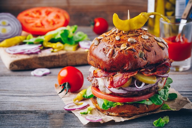 Hausgemachter Burger mit Vollkornbrötchen und würzig eingelegten Paprikaschoten auf Holzhintergrund