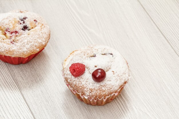 Hausgemachter Cupcake bestreut mit Puderzucker und frischer Minze auf Holzbrettern mit Kopierraum.