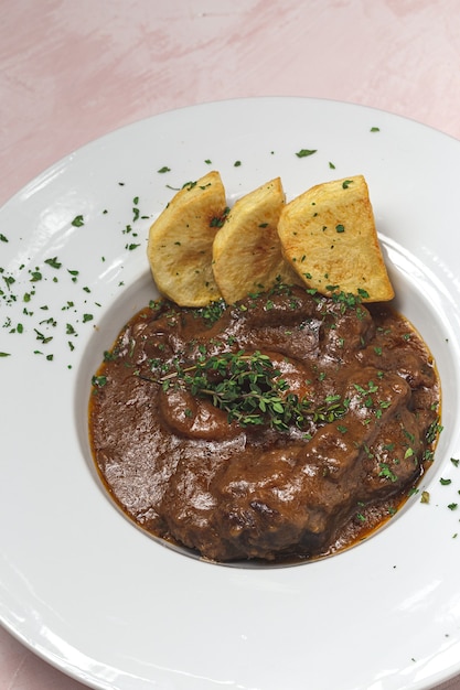 Hausgemachter Eintopf aus Osso Buco Fleisch mit aromatischer Kräutersauce, Rotwein und Pommes Frites