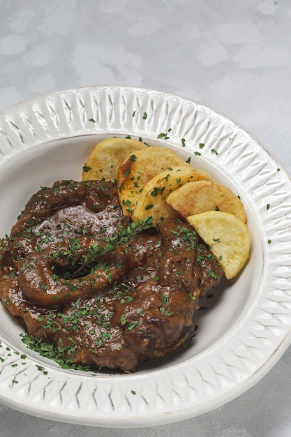 Hausgemachter Eintopf aus Osso Buco Fleisch mit aromatischer Kräutersauce, Rotwein und Pommes Frites