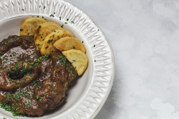 Hausgemachter Eintopf aus Osso Buco Fleisch mit aromatischer Kräutersauce, Rotwein und Pommes Frites