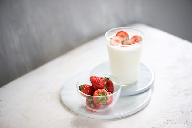 Hausgemachter Erdbeerjoghurt mit frischen Erdbeeren auf weißem Tisch