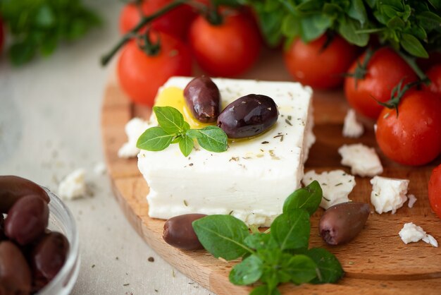 Hausgemachter Feta-Käse mit Olivenöl, Tomaten und Basilikum auf einem Holzbrett