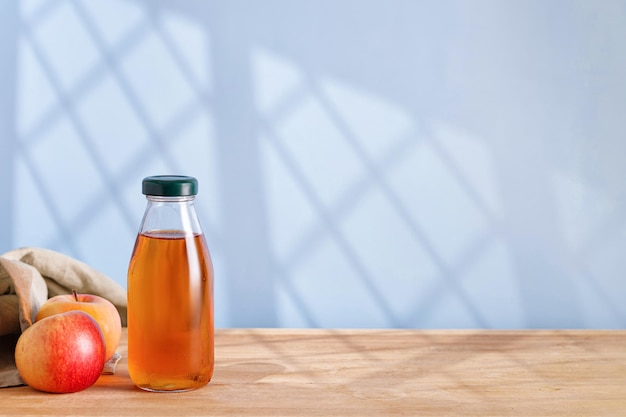 Hausgemachter frischer Apfelsaft in Glasflasche auf Holztisch Fensterschatten Kopierbereich