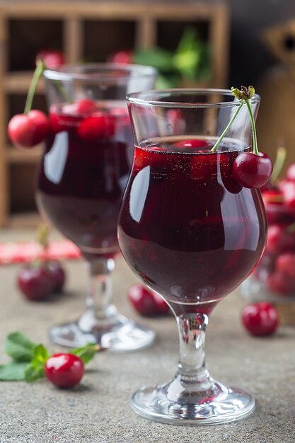 Hausgemachter frischer Kirschsaft in einem Glas mit frischen Beeren auf rustikaler Art.