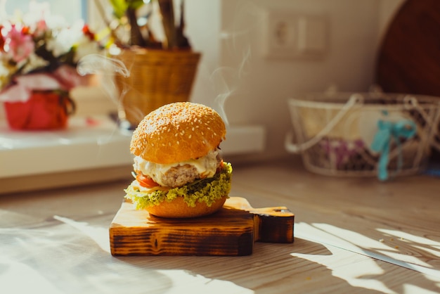 Hausgemachter gegrillter Rindfleischburger mit Salat, serviert auf Holzbrett in der Küche