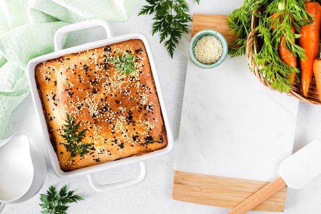 Hausgemachter geschlossener Kuchen mit Gemüse auf weißem Betonhintergrund Zutaten für einen Kohl- und Karottenkuchen auf dem Tisch