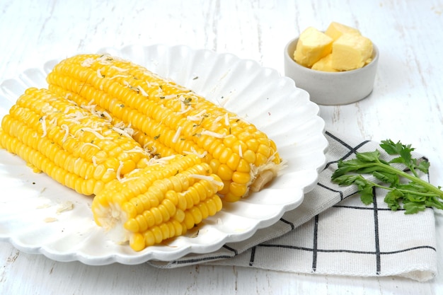 Hausgemachter goldener Zuckermaiskolben mit Butter und Käse auf weißem Tisch