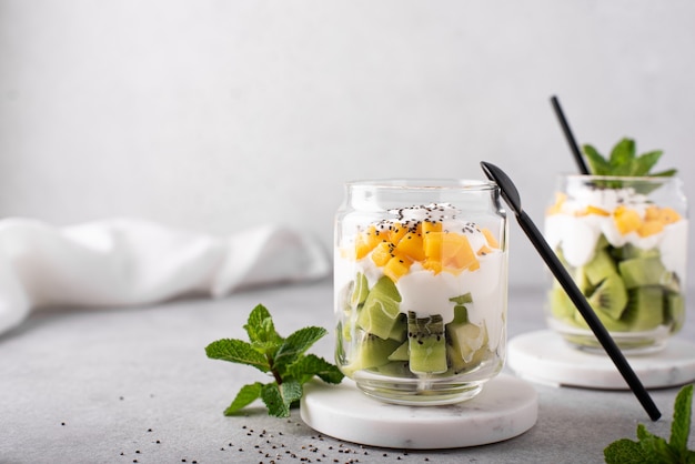 Hausgemachter griechischer Joghurt mit Kiwi- und Mangoscheiben in einem Glas, Nahaufnahme