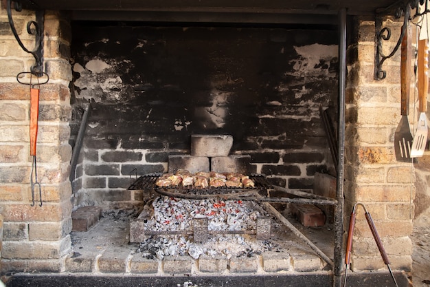 Hausgemachter Grill im Kamin. Braten von Fleisch auf einem Gitter. Gemütliche Atmosphäre und Hausmannskost.