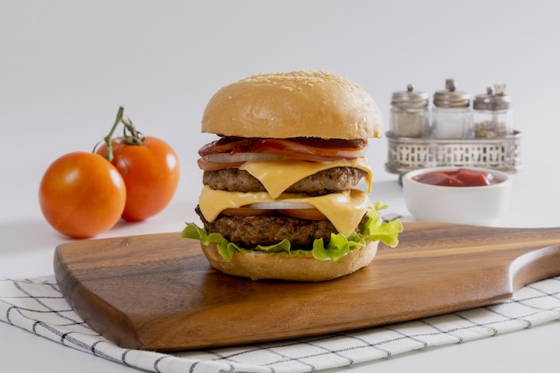 Hausgemachter Grillkäseburger mit Salat auf Holzbrett