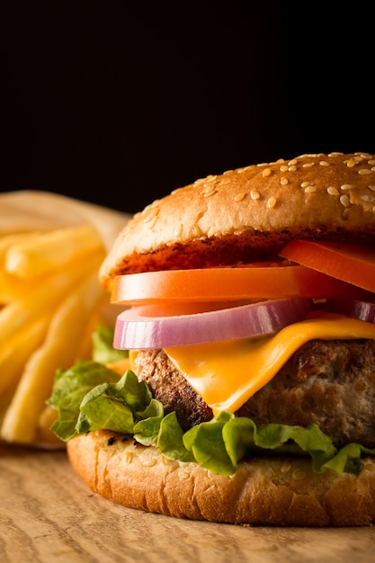 Hausgemachter Hamburger mit Rindfleisch, Zwiebeln, Tomaten, Salat und Käse. Frischer Burger nah oben auf hölzerner rustikaler Tabelle mit Kartoffelfischrogen, Bier und Chips. Cheeseburger.