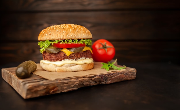 Hausgemachter Hamburger mit Salat, Tomate, Käse und Gurke auf einem Schneidebrett