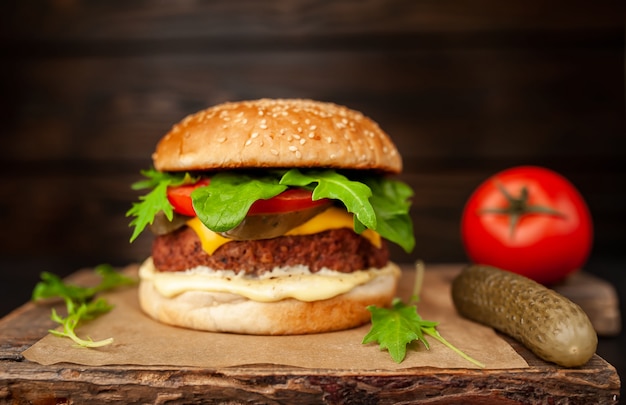 Hausgemachter Hamburger mit Salat, Tomate, Käse und Gurke auf einem Schneidebrett