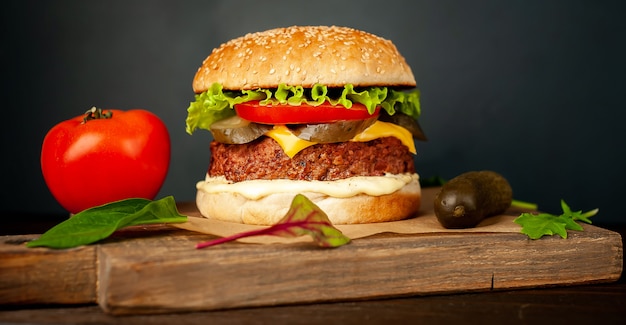 Hausgemachter Hamburger mit Salat, Tomate, Käse und Gurke auf einem Schneidebrett