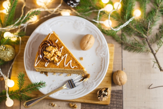 Hausgemachter Honigkuchen mit saurer Sahne auf einem Holztisch mit Rosinen und Nüssen