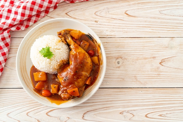 hausgemachter Hühnereintopf mit Tomaten, Zwiebeln, Karotten und Kartoffeln auf Teller mit Reis