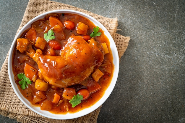 hausgemachter Hühnereintopf mit Tomaten, Zwiebeln, Karotten und Kartoffeln auf Teller