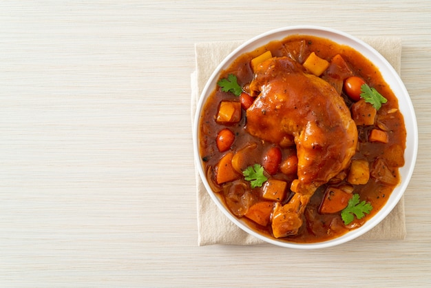 hausgemachter Hühnereintopf mit Tomaten, Zwiebeln, Karotten und Kartoffeln auf Teller