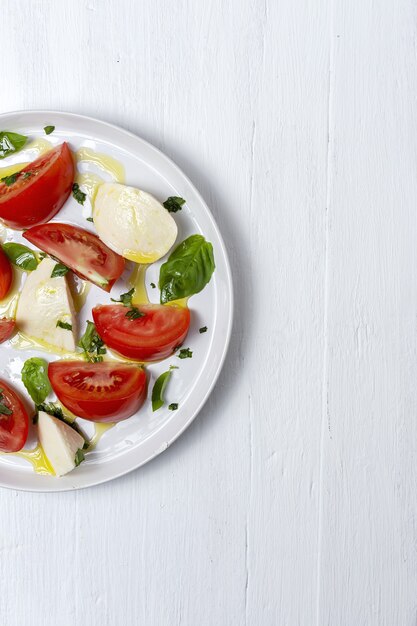 Hausgemachter italienischer caprese-salat mit geschnittenen tomaten, mozzarella, basilikum, olivenöl und salz.