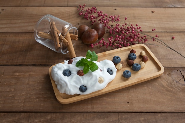 Foto hausgemachter joghurt mit blaubeeren und haselnüssen auf holzbrett