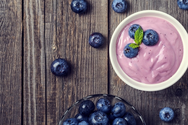 Hausgemachter Joghurt mit frischer Blaubeere auf einem hölzernen Hintergrund, Draufsicht.